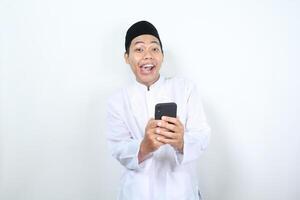 funny and amazed face of muslim asian man holding phone with looking at camera photo