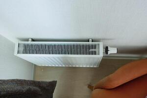 White radiator on grey white wall. apartment heating installation system, photo