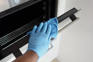 hand in gloves Cleaning the kitchen oven. photo