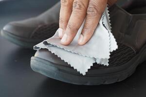 Men wipes his leather shoes with a wet cloth photo