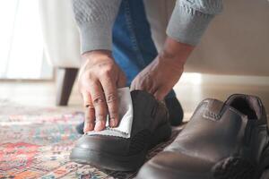 Men wipes his leather shoes with a wet cloth photo