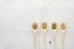 Four wooden spoons with various spices on a white tableware surface photo