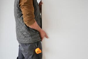 a man is measuring a wall with a tape measure photo