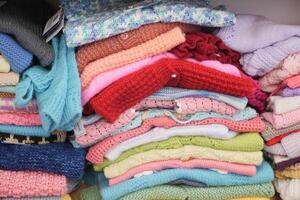 Bunch of knitted warm sweaters with different knitting patterns. photo