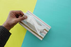 hand pull out a piece of tissue from tissue paper box photo