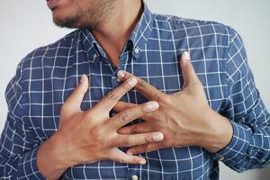 young man suffering pain in heart and holding chest with hand photo