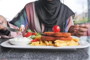 women eating Chicken schnitzel served with potato chips photo