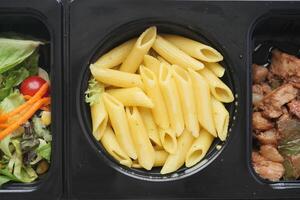 a close up of a bowl of pasta next to a bowl of salad and a bowl of meat photo