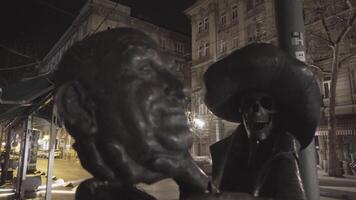 Budapest, Hungary CIRCA 2015 - Man with Two Faces - the statue in front of opera house - a skeleton with a rifle for a body holds the head of the opposing human body out in front of him video