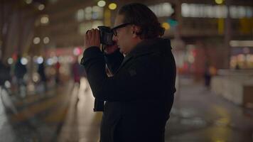 Male Traveler Taking Photo on Crowded Urban City Street at Night video