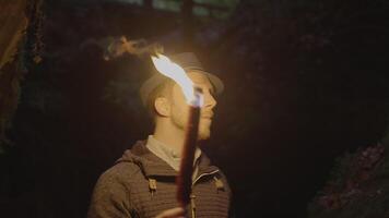 Mens Holding een brandend zaklamp verkennen Woud grot landschap in donker nacht video