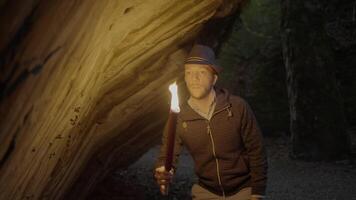 Man Holding A Burning Torchlight Exploring Forest Cave Landscape In Dark Night video