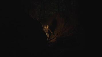 homem segurando uma queimando luz da tocha explorando floresta caverna panorama dentro Sombrio noite video