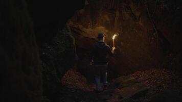 Man Holding A Burning Torchlight Exploring Forest Cave Landscape In Dark Night video