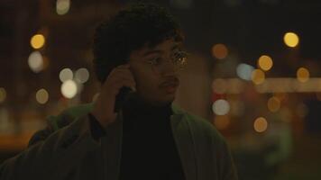 joven hombre con negro Rizado pelo esperando solitario a tren estación a noche video