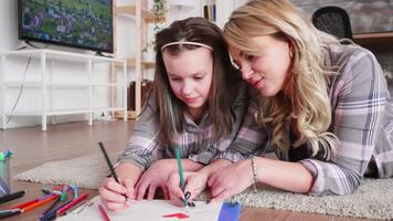 Mother and daughter lying on the floor carpet in living room drawing. video