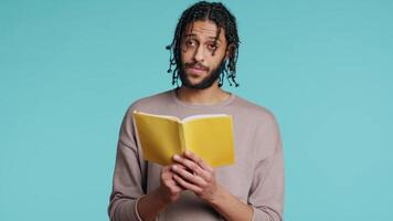 middle eastern man reading book from publisher aloud, telling story, enjoying hobby. BIPOC person narrating literature novel, doing critique essay, isolated over studio background, camera B video