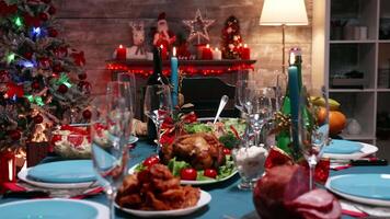 Zoom in shot of delicious food for christmas reunion on the table. Christmas decoration. Xmas celebration in decorated room full of globe decorations and christmas tree with fireplace, big festive dinner meal for large family video