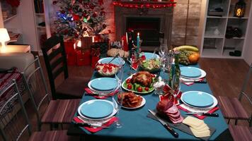 Table full of delicious and tasty food for christmas celebration of a big family. Xmas celebration in decorated room full of globe decorations and christmas tree with fireplace, big festive dinner meal for large family video