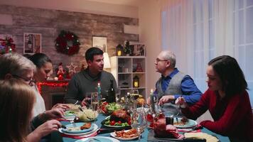 abuelos celebrando invierno Días festivos con hijas alegre familia. tradicional festivo Navidad cena en multigeneracional familia. disfrutando Navidad comida banquete en decorado habitación. grande familia reunión video