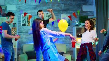 alegre jovem mulher às uma festa fazendo robô dança movimentos. grupo do pessoas festa dentro a apartamento com néon luzes, discoteca bola e uma muitos do álcool video