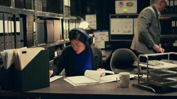 Agent extracting cryptic references found in classified records that may require further deciphering or analysis, archive room work. Law officer trying to break codes to find details. Camera B. video