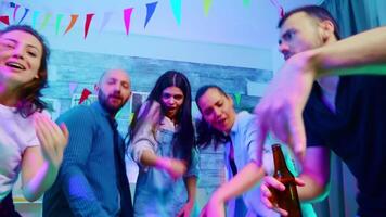 Group of excited friends dancing at wild college party looking at the camera in a room full of neon lights video