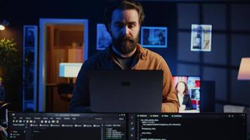 Portrait of smiling developer writing complex binary code scripts on laptop terminal. Cheerful remote IT employee standing in home office, using programming to safeguard consumer data, camera B video