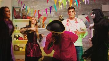bärtig Pirat Singen Karaoke beim Halloween Party. Gruppe von freunde im Kostüme sind Tanzen und haben Spaß im das Hintergrund video