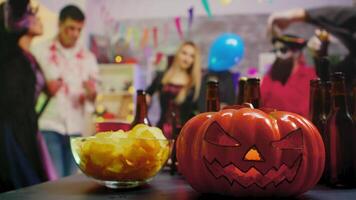 Scary pumpkin on the party while group of people are dancing celebrating halloween in the background video