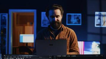 Portrait of smiling developer writing complex binary code scripts on laptop terminal. Cheerful remote IT employee standing in home office, using programming to safeguard consumer data, camera A video