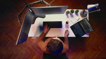 Top down view of remote worker typing code in personal office, using javascript language to develop software application. It specialist using multimonitor desktop setup to finish project, aerial shot video