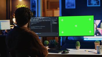 Self employed man doing IT support job from apartment personal office, coding on green screen PC. Software developer writing lines of code on mockup computer at home, camera A video