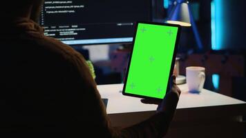 software ontwikkelaar programmering in huis kantoor, kruiscontrole lijnen van code tussen groen scherm tablet en pc scherm. het beheerder Holding mockup portable apparaat terwijl codering Aan computer video