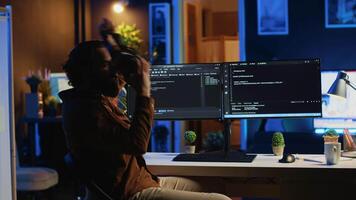 distansarbete programmerare använder sig av trogen vr glasögon i Hem kontor till do javaScript programmering. den expert- bär hög tech virtuell verklighet headsetet till visualisera rader av koda, kamera en video