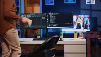 ingenjör anländer i Hem kontor med råna av kaffe i hand, redo till Start kodning använder sig av javascript. den expert- början avlägsen arbete flytta, innehav kopp av te, uppdatering företag programvara, kamera en video