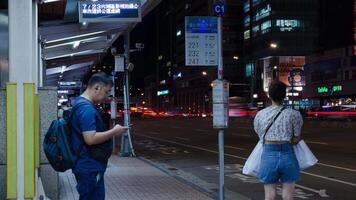 night view timelapse landscape at bus stop in the city center of Taipei capital city of Taiwan with crowded passenger people pedestrian get on get off bus at bus stop video