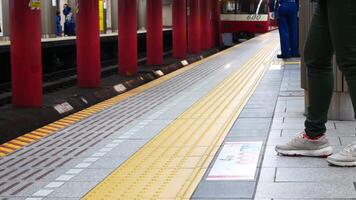 laag hoek visie naar de tokyo metro platform Bij trein station terwijl mensen aan het wachten voor aankomst naderen video