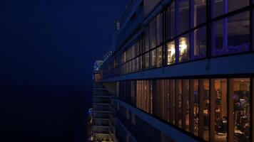 view to the back aft of the cruise ship from front deck area with view of the passenger cruise ship while cruising in the internation open sea in night time video