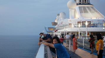 view the top deck of the Spectrum of the sea cruise ship of royal caribbean cruise line with many passengers relaxing in the early morning time while cruising in the sea video