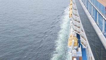 view to the front of the cruise ship from aft back deck area with side view of the passenger cruise ship while cruising in the sea in day time with many lifeboats video