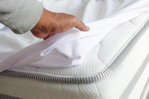 Placing the white sheet on the mattress for added comfort photo