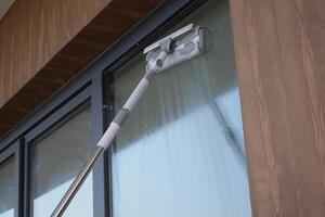 Rubber squeegee cleans a soaped window. photo