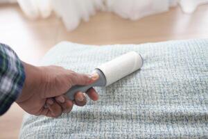 using an adhesive roller to remove lint and fluff from a bed . photo