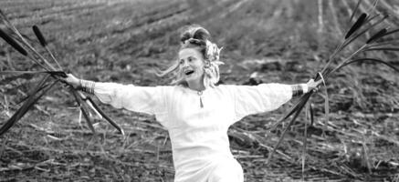 Cheerful young  woman with reeds dances in colored smoke in a field. photo