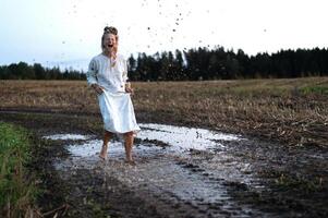 Cheerful young  woman with reeds dances in colored smoke in a field photo