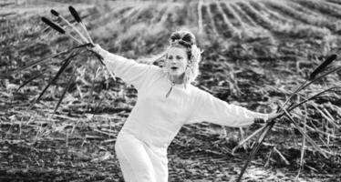 Cheerful young  woman with reeds dances in colored smoke in a field. photo