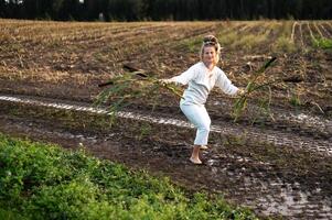 Cheerful young  woman with reeds dances in colored smoke in a field. photo