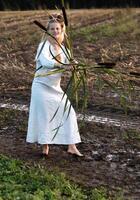 Cheerful young  woman with reeds dances in colored smoke in a field. photo