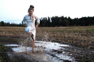 Cheerful young  woman with reeds dances in colored smoke in a field photo